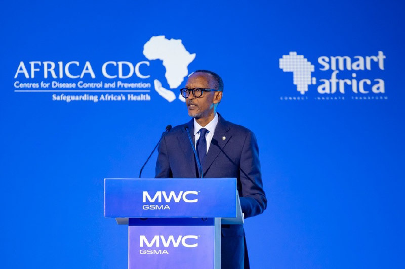 A keynote speaker delivers a speech at the MWC GSMA event, standing at a podium with logos of Africa CDC and Smart Africa projected on a blue background.